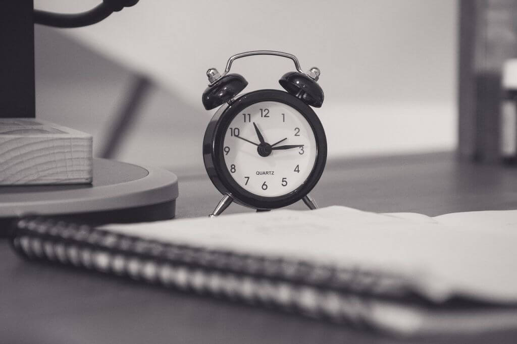 alarm clock next to sketch pad to keep track of deadlines